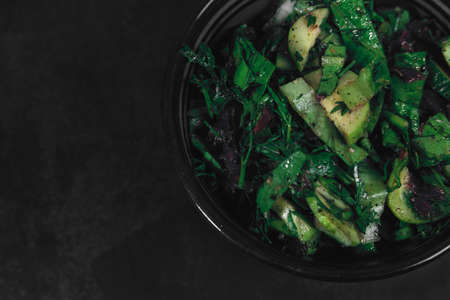 Bowl with salad of organic vegetables and herbs on dark textured background. Top View, space for text. Organic eco food. Carrots with green tops tied with rope. Healthy diet. Freshly cut vegetablesの写真素材