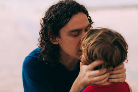 Father's Day. Dad with his little son. Family walk with a child. Outdoor activities for family. Dad hugs and kisses his son on the street. Family relationship between child and adultの写真素材