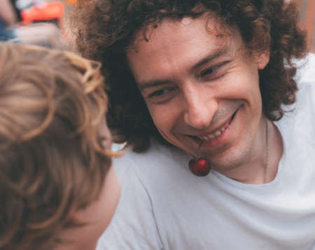 Father's day. Dad and son. Little son feeds dad ripe cherries on the beach. Happy family father and...