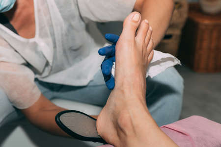Peeling feet pedicure procedure in salon. Hardened leather grater. Leg of a young woman in Spa. Peeling of heels. Professional pedicure process. Concept of beauty care and health.の写真素材