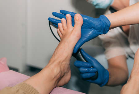 Peeling feet pedicure procedure in salon. Hardened leather grater. Leg of a young woman in Spa. Peeling of heels. Professional pedicure process. Concept of beauty care and health.の写真素材
