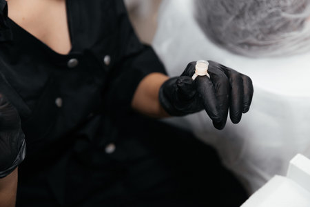 Finger in a black glove is wearing an empty permanent paint ring. Close-up of pigment container for eyebrow or lip tattoo. Beauty procedure preparation.の写真素材