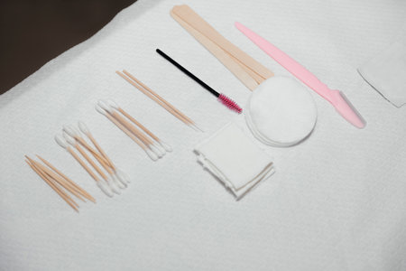 Sterile napkins, cotton pads, wooden sticks, pink brush, buds. Beautician tools for making eyebrows makeup. Facial care and make up in a professional beauty salon.の写真素材