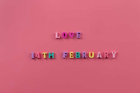 The word "LOVE 14th February" banner. Multicolored letters on pink background. Theme of love on Valentines day. Loving, positive emotions. Happy holiday. The concept of celebration and love.の写真素材