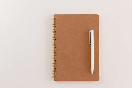 Spiral closed brown notebook and white pen. Layout and flat lay with place for text isolated on...