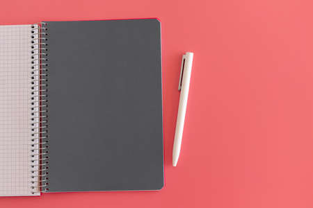 Spiral opened notebook with gray sheet and white pen. Layout and flat lay with place for text on a delicate pink background. Back to school. Top view, copy space. High resolution. Student workplaceの写真素材