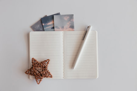 Blank opened notebook in line with pen and brown decor star on white background. Decorated with pictures clouds, space. Top view of open empty notebook. Astrologer's desk. Plan for the dayの写真素材