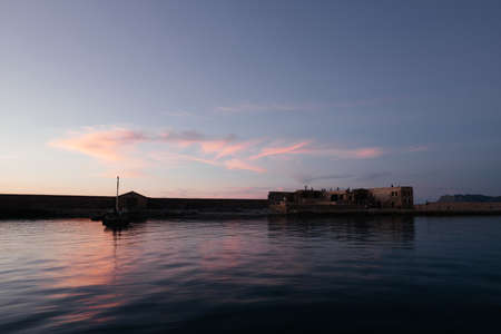 Venetian harbor near lighthouse in old harbor of Chania with nice sunset reflection on water of sea; Crete; Greece. long exposure. People watching sunset from the harbor. nice backgroundの写真素材