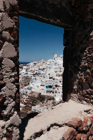 View of Oia town with mills in stone frame in Santorini island in Greece. Summer vacation and...