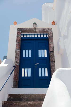 Beautiful blue door on white facade of greek architecture in Oia city, Santorini island, Greece, Europe. Beautiful details of the island of Santorini. Famous travel destination with blue sky viewの写真素材