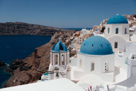 View of Oia town with church and blue dome in Santorini island in Greece. Summer vacation and holiday concept, luxury travel. Wonderful scenery, cruise ships and white architecture. amazing sceneryの写真素材
