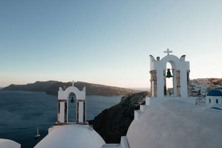 View of Oia town with church on sunset time in Santorini island, Greece. Summer vacation and holiday concept, luxury travel. Wonderful scenery, cruise ships and white architecture. amazing sceneryの写真素材