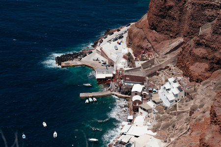Top view of port with boats and mountain rocks of Oia, Santorini, Greece. Blue Aegean sea and boats near pier. View from above, top view, drone. Beautiful landscape with wavesの写真素材