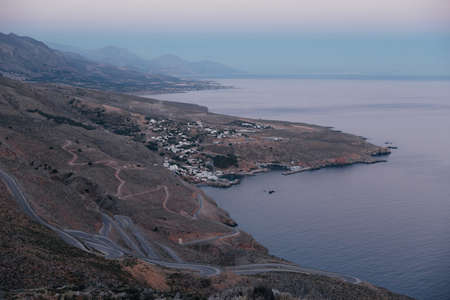 Amazing winding backroads of the wild southern coast of the island of Crete, Greece, with view on sea and blue sunset sky. Wonderful landscapes, mountains and the sea on the coastline. copy spaceの写真素材