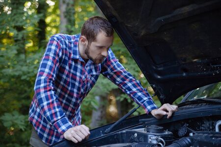 The guy opened the hood of the car and looks at the engine. Emergency stop and car repairの写真素材