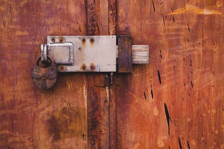 Abstract colorful wall texture and background. Close-up iron surface with old paint and rust and with the padlockの写真素材