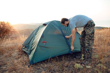 Autumn trekking in the mountains. Tourist sets up a tentの写真素材