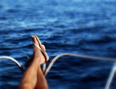 Boat travel conceptual photo - Legs on the prowl of the boat and the sea as background. Soft focus blur on the edges 
の写真素材