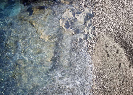 Beautiful rocky beach with some footprints on the sandの写真素材