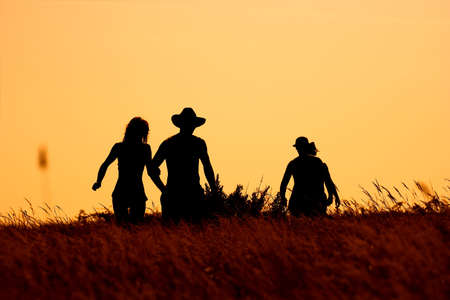 In silhouette, group of young people enjoying a day in the nature. Photographed into the light and faces are not recognizable.の写真素材