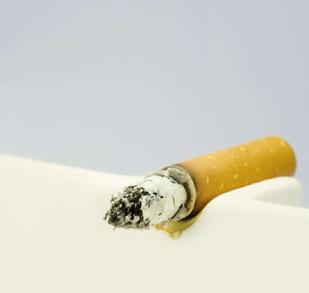 A burning cigarette in a white ashtrayの写真素材