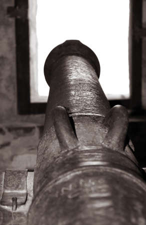 Old cannon used to defend the castle pointed trough the windowの写真素材