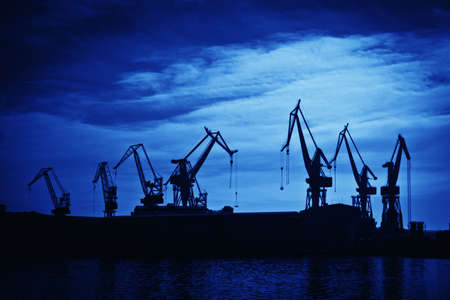 Shipyard cranes against blue sky, artistic toned photoの写真素材