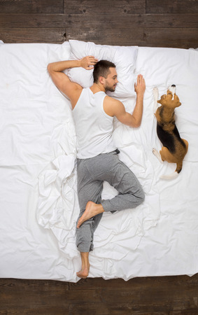 Young man relaxation on the bed top view sleeping with a dogの写真素材