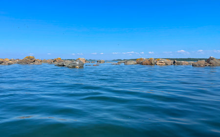A tranquil seascape featuring beautiful rocks set beneath a clear and bright blue skyの写真素材