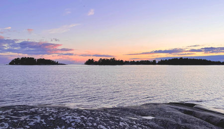 A Beautiful and Tranquil Sunset Over Serene Islands Surrounded by Calm Waters and Natureの写真素材