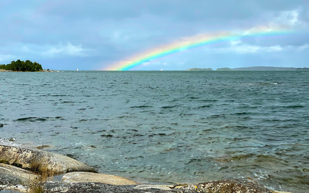 A scenic waterscape with a colorful rainbow over the sea and a tranquil atmosphereの写真素材