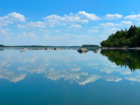 Tranquil serene lake beautifully reflecting under clear blue skies, creating a peaceful atmosphereの写真素材