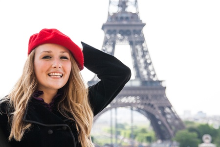 A Beautiful girl, wearing a red hat and smiling, in front of the Eiffel Tower の写真素材
