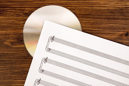 Music sheet and CD drive on wooden background. Old and new technology in music.の写真素材