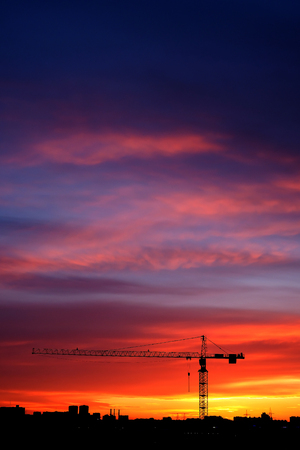 Industrial construction cranes and building silhouettes at sunseの写真素材