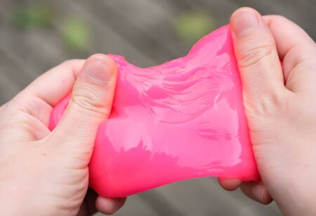 Pink anti stress toy slime in hands. Fighting anxiety and stress. Creative game experiment for children.の写真素材