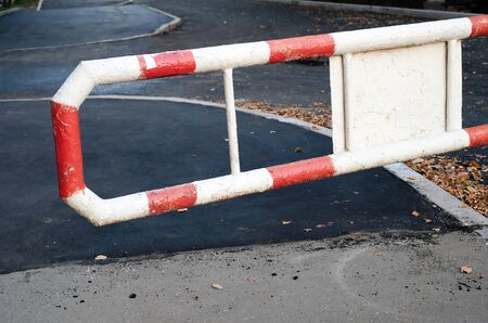A red and white metal barrier before entering the private territory. Pavement repair, asphalt...