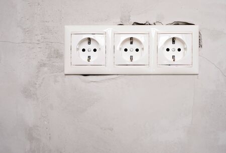 Electric EU socket outlet on gray concrete wall background. Repair in an apartment or in office,...