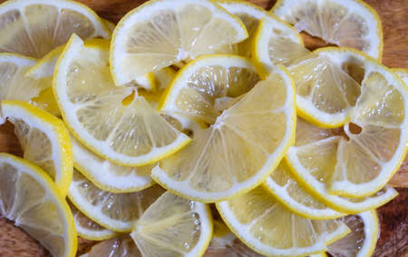 Ripe juicy yellow lemons slices on beautiful wood background. Prevention of colds in the cold season, ingredient for lemon tea or homemade lemonade.の写真素材