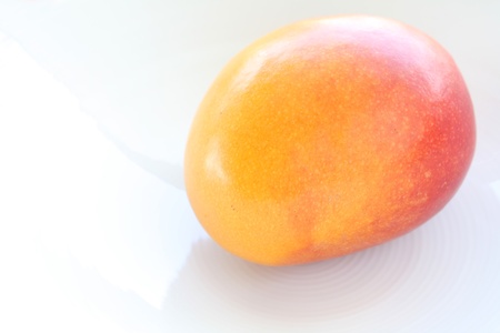 Fresh whole mango on a white plateの写真素材