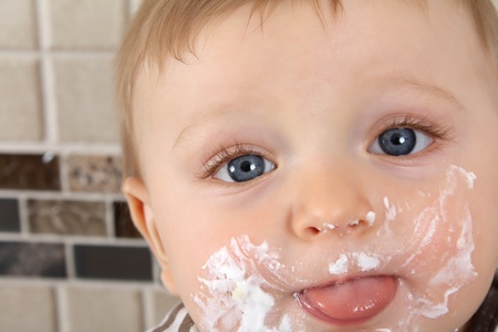 Baby boy sticking out his tonge with icing covered cheeksの写真素材