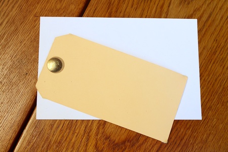 Yellow and white tag with a pin on wooden tableの写真素材