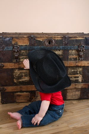 Cute baby boy sitting in front of an antique trunkの写真素材