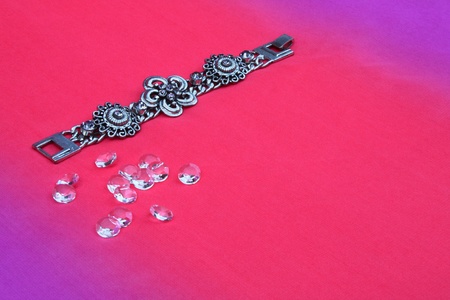 Silver bracelet with purple gems on pink background