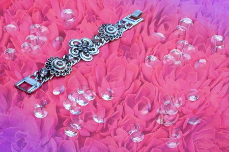 Silver bracelet on pink floral background with gemsの写真素材