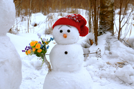 Snowman in a red hat with flowers.の写真素材