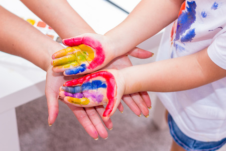 Hands of a child painted with bright colors. Mum holds the hand of his daughter.の写真素材