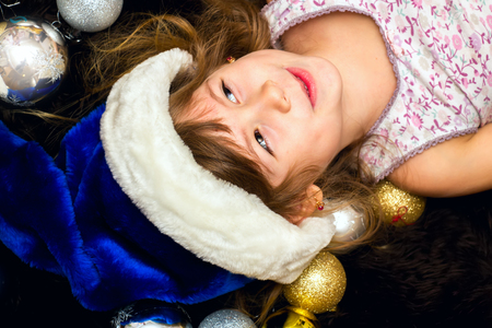Little cute girl lying on the floor with Christmas balls.の写真素材