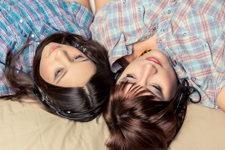 Mother and daughter listening to music in bed.の写真素材