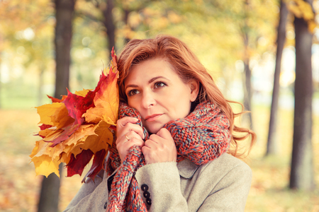 Beautiful blonde in a coat walking in the autumn park.の写真素材
